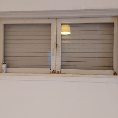 חלון זכוכית עם תריסים סגורים ומנורה משתקפת