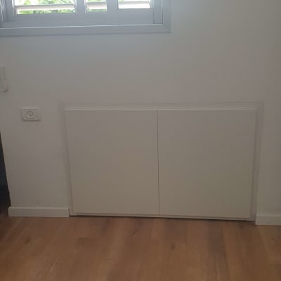 ארון עץ לבן מתחת לחלון עם תריסים