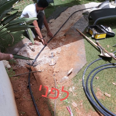 אדם עובד על צינור בגינה עם כלים