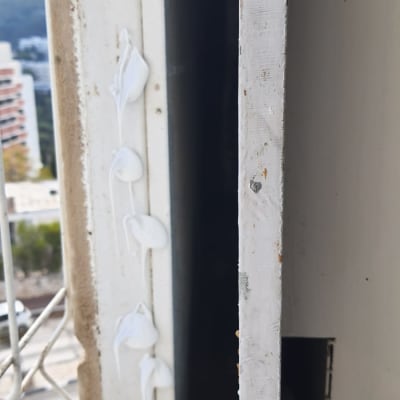 חומר איטום לבן על מסגרת חלון מתכתית