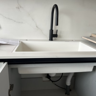 כיור מטבח עם ברז שחור וצנרת גלויה מתחת