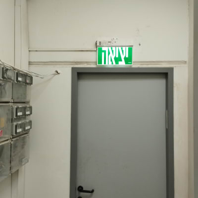 שלט יציאה ירוק מעל דלת אפורה