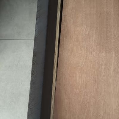 לוח עץ מונח על רצפה ליד קיר אפור