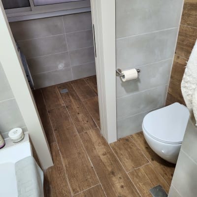 רצפת עץ חדשה בחדר אמבטיה עם קירות אריחים