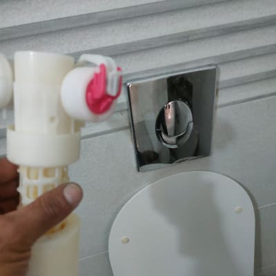 יד מחזיקה חלק פלסטיק ליד אסלה וכפתור הדחה