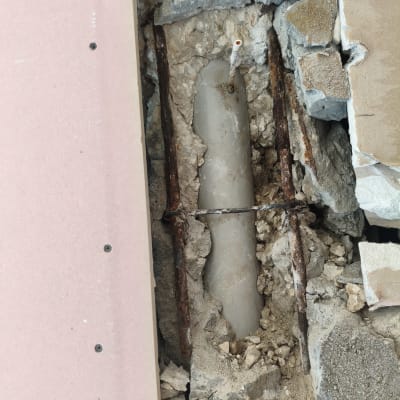 צינור חשוף בתוך קיר שבור עם ברזלים חלודים