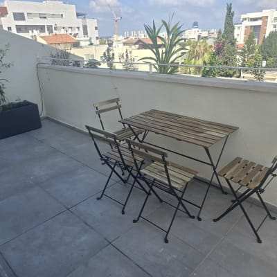מרפסת עם שולחן וכיסאות עץ וצמחייה