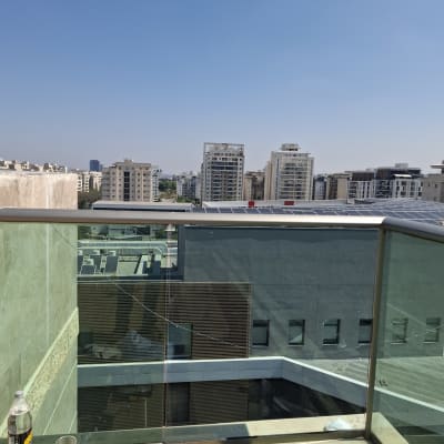 מעקה זכוכית עם נוף לעיר ובקבוק על המעקה