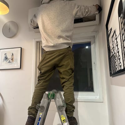 אדם על סולם מתקין מזגן על קיר