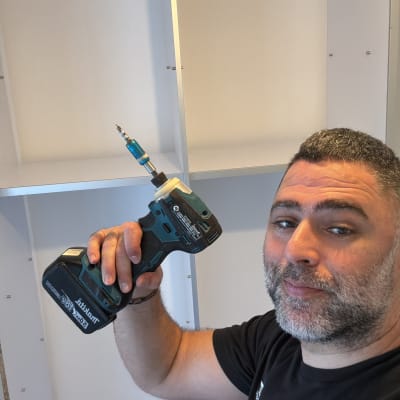 אדם מחזיק מקדחה ליד ארון בבנייה