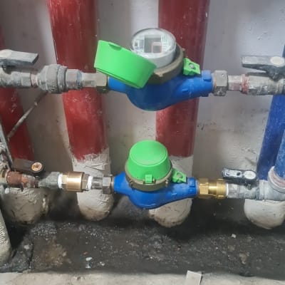 מד מים כחול עם מכסה ירוק על צינור