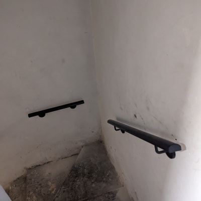 מעקה שחור מותקן על קיר מדרגות ישנות