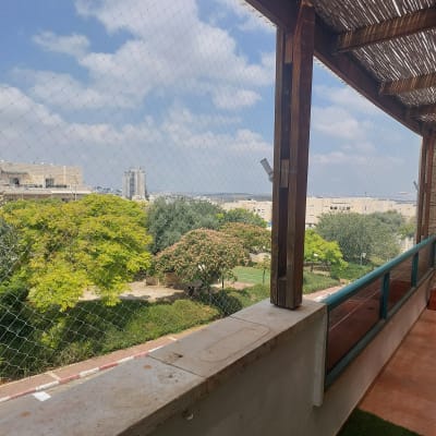 רשת יונים על מרפסת עם נוף לעצים ושמיים