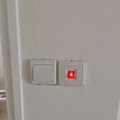 שני מתגים על קיר, אחד עם נורית אדומה דולקת