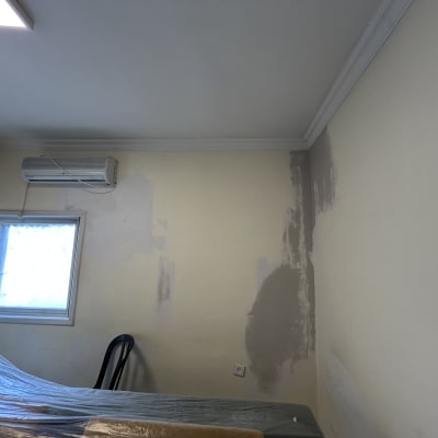 קיר עם תיקוני צבע וטיח, כיסוי פלסטיק על רהיטים