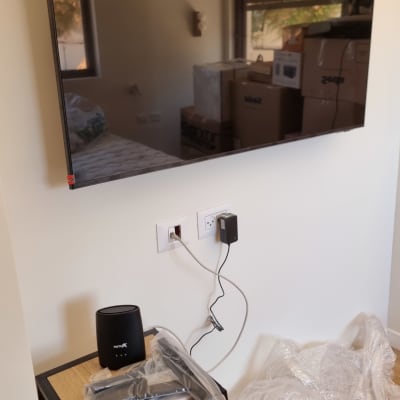 טלוויזיה מותקנת על קיר עם שולחן קטן וכלים