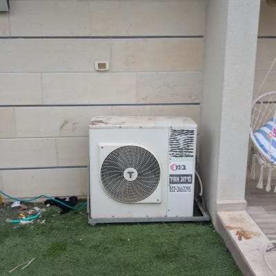 יחידת מיזוג אוויר מותקנת ליד קיר חיצוני עם כיסא תלוי