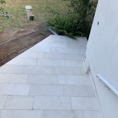 עבודות ריצוף חוץ באריחי אבן בהירים בשביל גישה לצד דשא