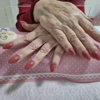 ידיים עם ציפורניים מטופחות על כרית ורודה