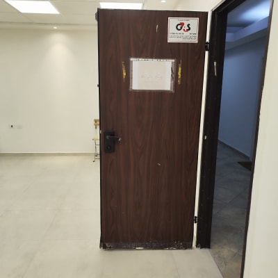 דלת חומה עם ידית שחורה ושלט אבטחה