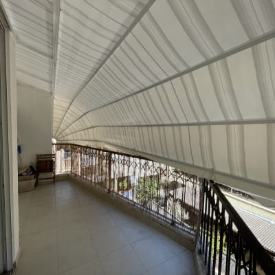 מרפסת עם סוכך לבן מעל מעקה ברזל