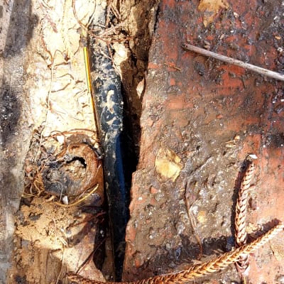 צינור שחור שבור בין לבנים ואדמה