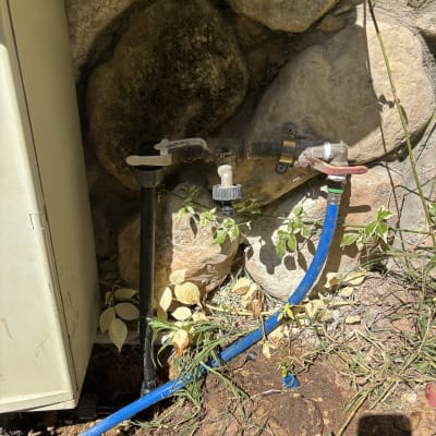 ברזים וצינורות ליד קיר אבן בגינה