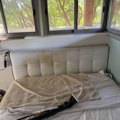 מיטה עם ראש מיטה מלוכלך וכלי ניקוי על המיטה