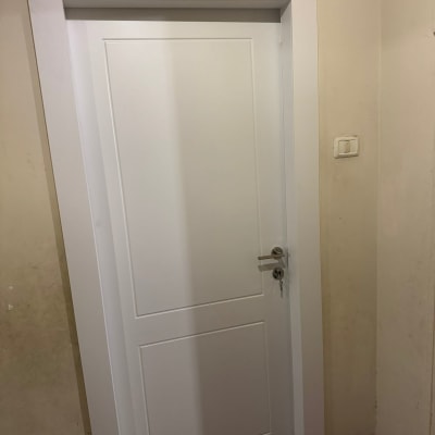 דלת לבנה עם ידית כסופה על קיר בהיר