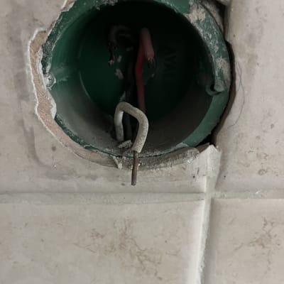 חוטי חשמל חשופים בקופסת חיבורים בקיר