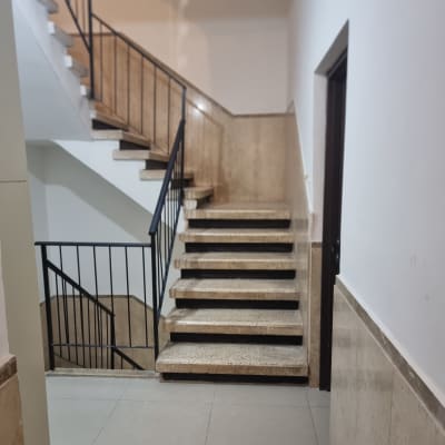 גרם מדרגות עם מעקה מתכת וקירות לבנים