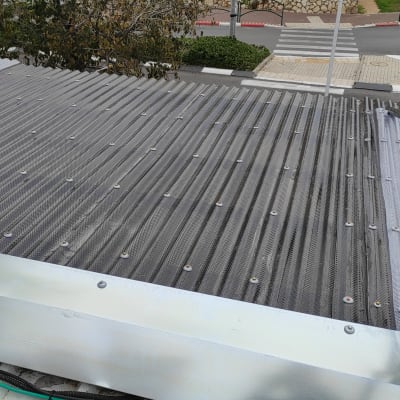 גג מתכת עם ברגים ומעקה מתכת שחור