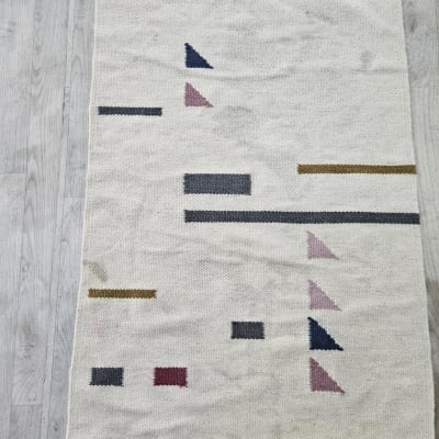 שטיח עם דוגמאות גיאומטריות על רצפה אפורה