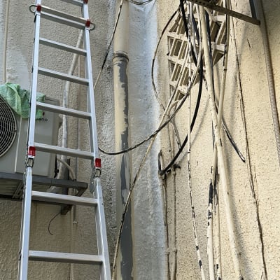 סולם ליד קיר עם צינורות וחוטים, עבודה בתחום האיטום