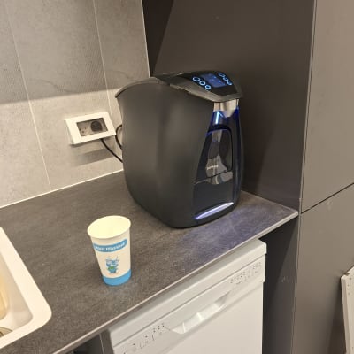 מכונת קפה וכוס חד פעמית על משטח מטבח