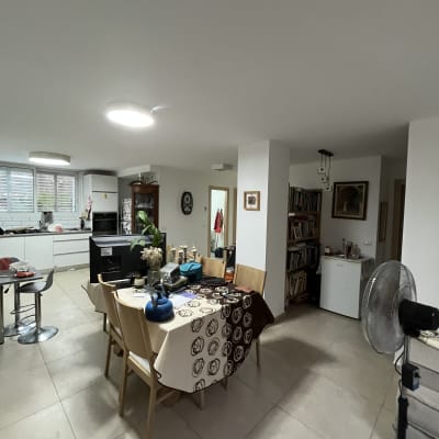 חדר אוכל עם שולחן מכוסה מפה, כיסאות ומאוורר