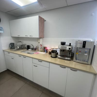 מטבח עם ארונות לבנים ומכונת קפה על השיש