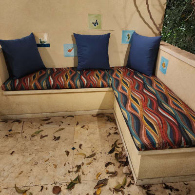 ספסל מרופד עם כריות כחולות ודוגמת פסים צבעונית