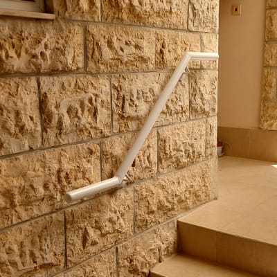 מעקה לבן על קיר אבן במדרגות פנימיות