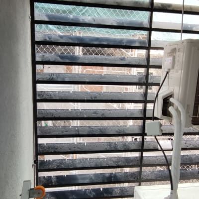 רשת מתכת על חלון עם מזגן וצינורות