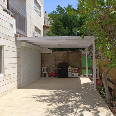 פרגולה מאלומיניום בחצר עם ריצוף אבן