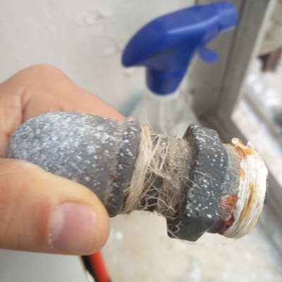 חיבור צינור עם חוטי איטום ביד של אדם