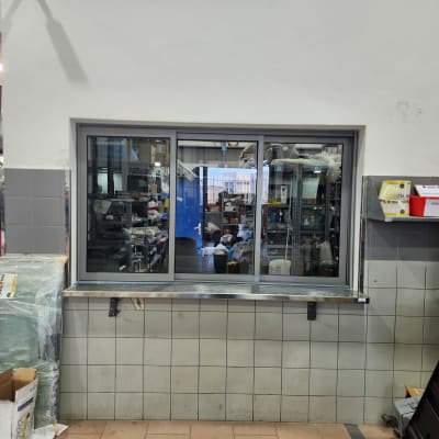 חלון אלומיניום עם מסגרת כסופה במרכז הקיר