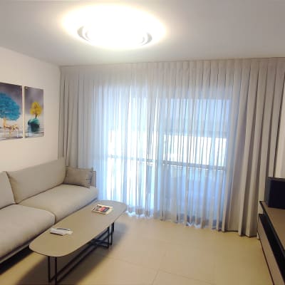 וילון לבן שקוף תלוי על חלון גדול בסלון