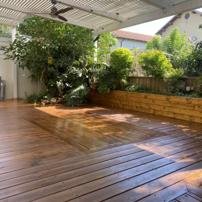 דק עץ עם גינה מוגבהת וצמחייה ירוקה