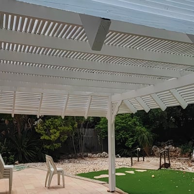 פרגולה לבנה מעץ מעל דשא סינתטי