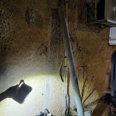 צינור ואביזרי חיבור ליד קיר חיצוני בלילה