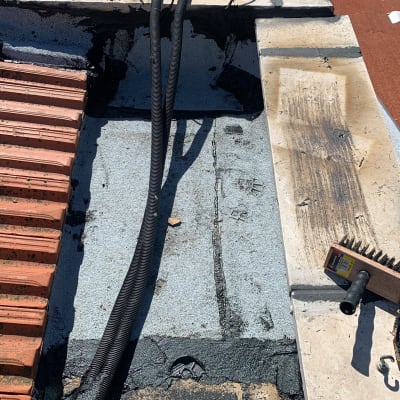 חומר איטום שחור על גג עם כבלים ומברשת