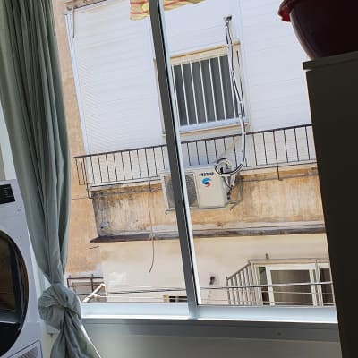 מכונת כביסה ליד חלון עם וילון פתוח