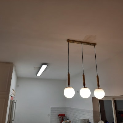 שלושה גופי תאורה תלויים מהתקרה בחדר